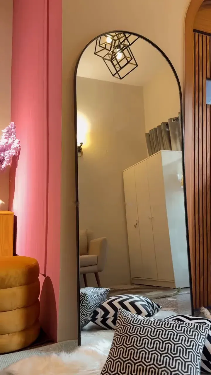 AAINA arched floor mirror in a furnished room with cushions and a rug in front of it