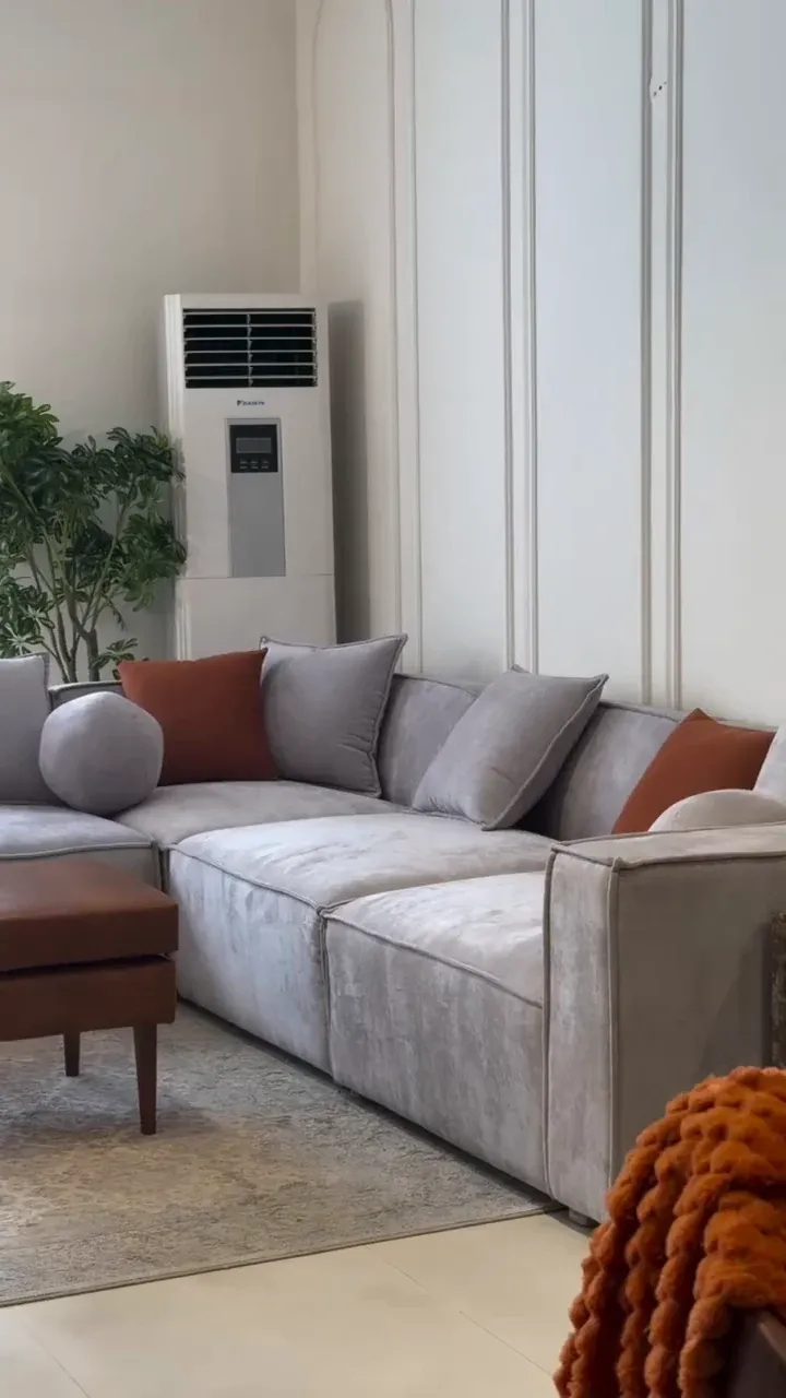 Grey modular L-shape sofa with rust and grey cushions in a living room — photograph of the BADAL sofa supplied by the showroom