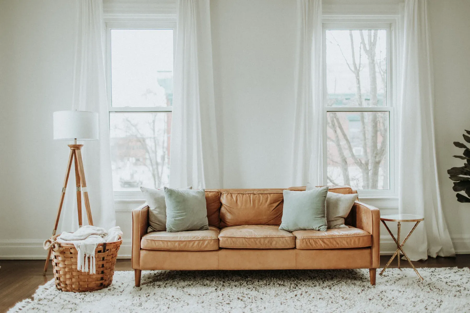 Warm tan sofa with pastel cushions beside large windows