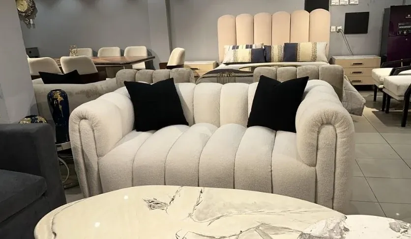 Cream channelled boucle sofa with two black cushions on the showroom floor — photograph of the MALAI sofa