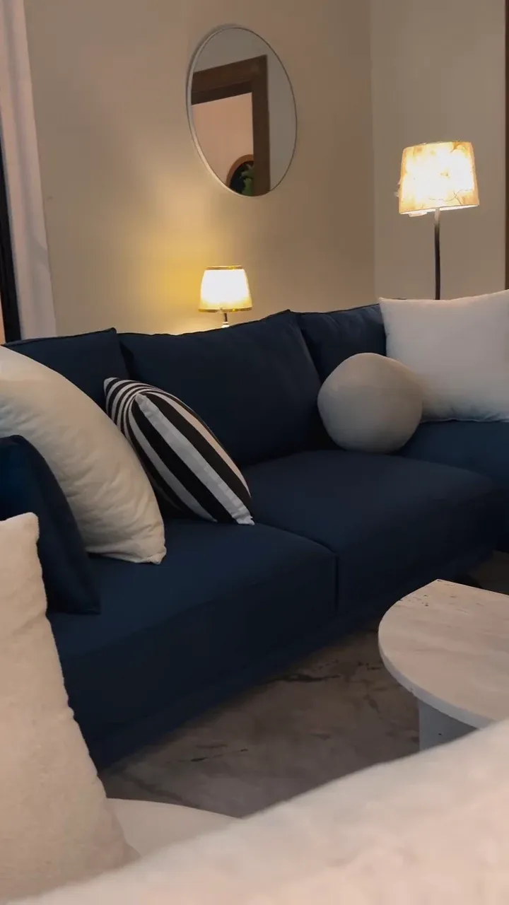 Deep blue fabric sofa with cream and striped cushions in a lounge — photograph of the NEELAM sofa supplied by the showroom
