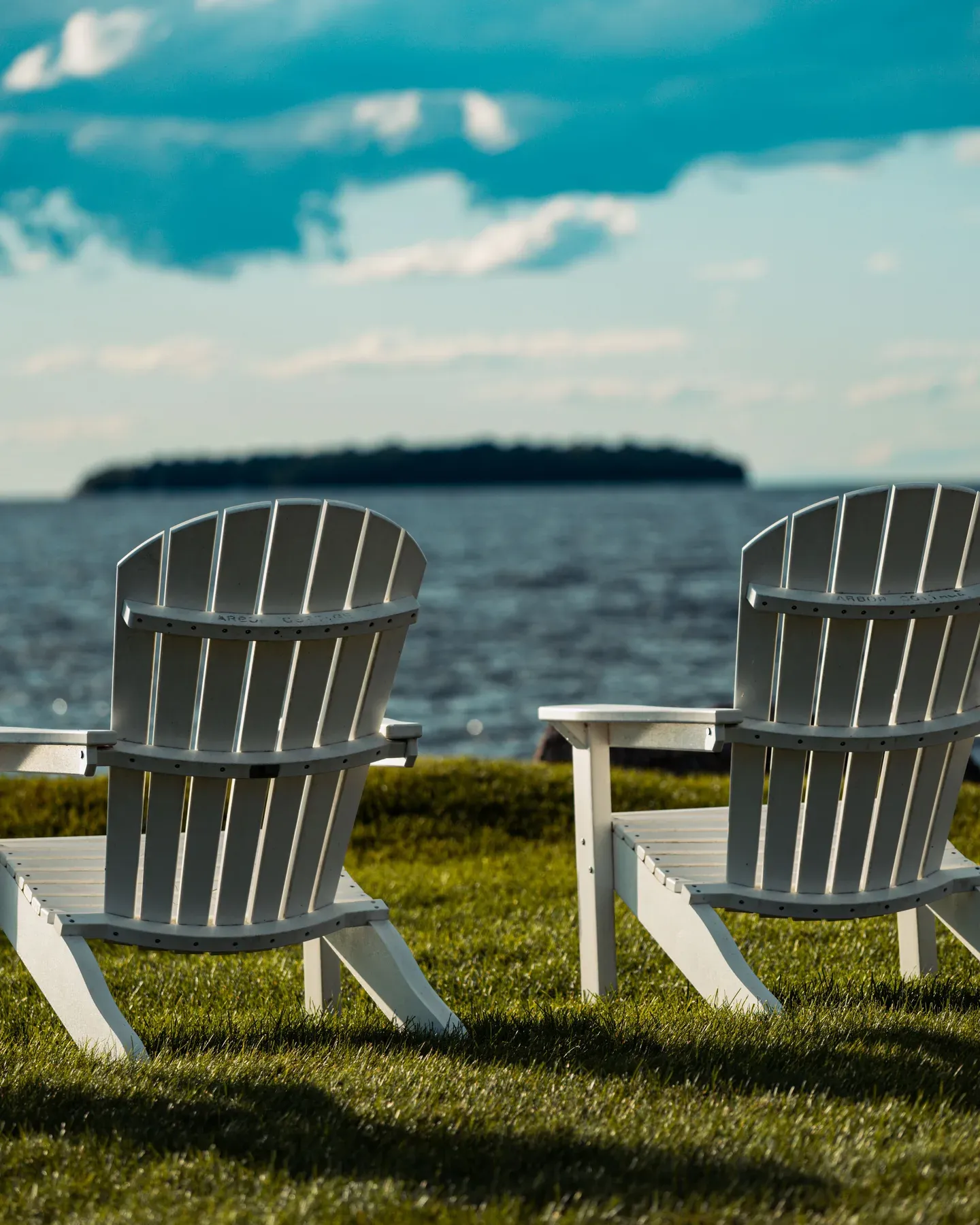 Pair of Adirondack garden chairs facing the water — reference image for the HAWA slatted garden chair
