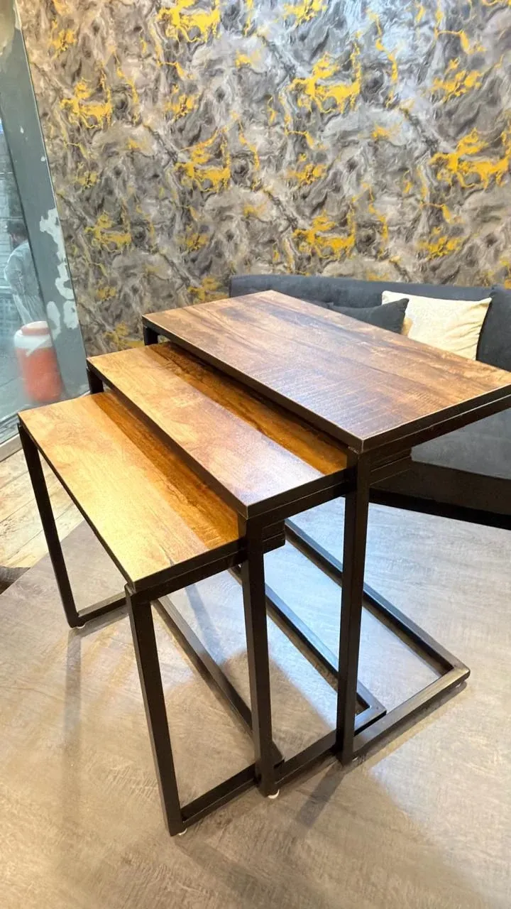 Three nesting tables with wood-look tops and black metal frames, stepped out — photograph of the SILSILA set at the showroom