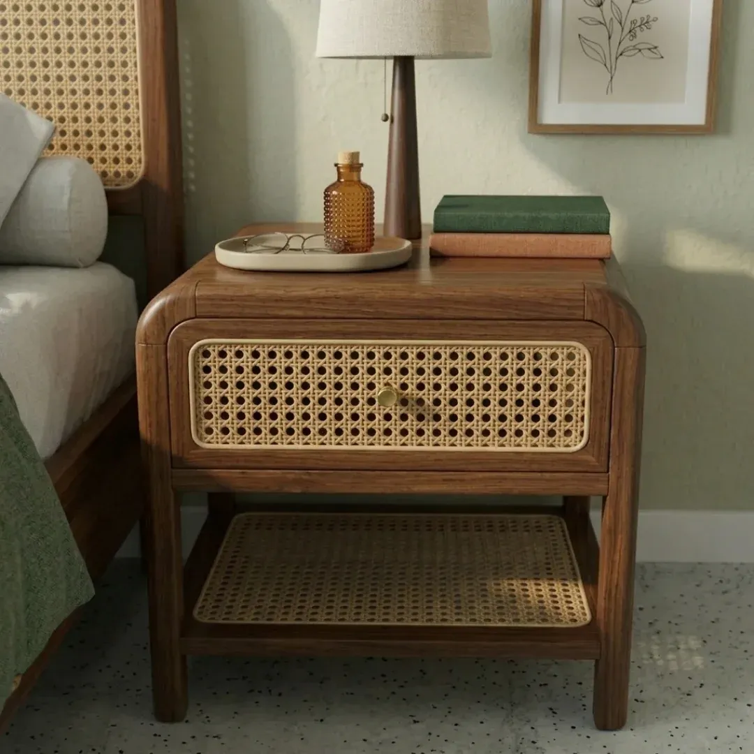 SUBAH Rattan Bedside Table in walnut brown and natural rattan, front view beside a bed with a lamp