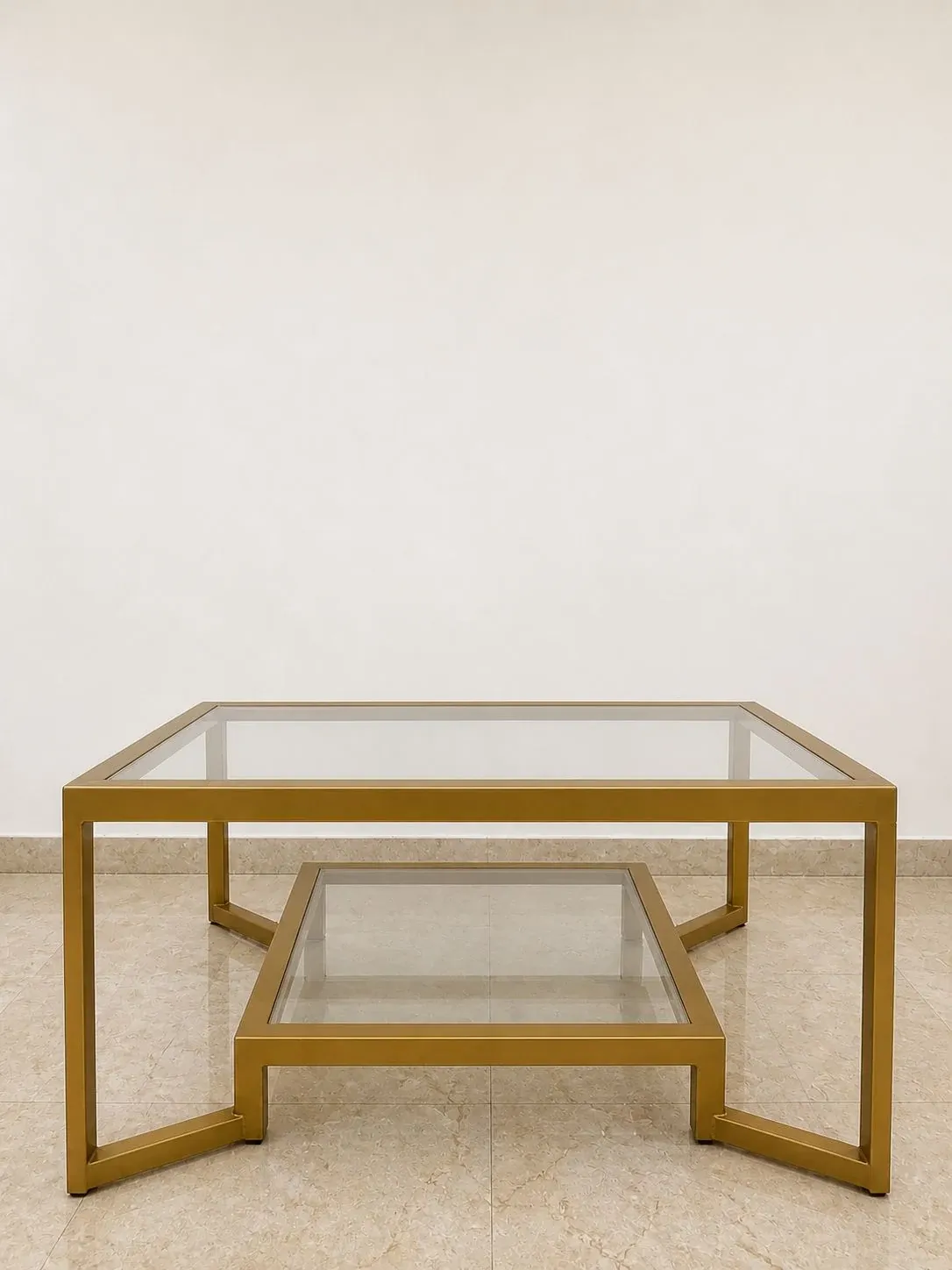 Two-tier coffee table with a gold-finish metal frame and clear glass top and shelf — photograph of the ZARI table